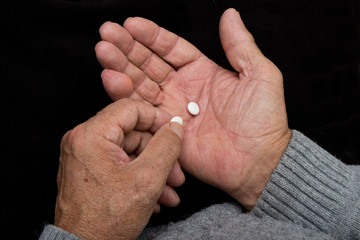 An elderly man holds a lot of  pills in old hands. Painful old age. Health care of older people