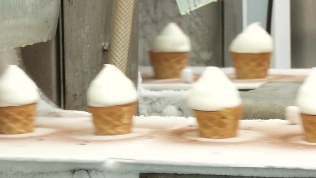 Ice cream in a cone. Filling of wafer cups with ice cream. White plombir in a waffle cup. Ice cream production line.