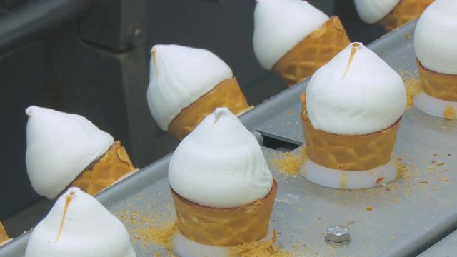 Ice cream in a cone. Filling of wafer cups with ice cream. White plombir in a waffle cup. Ice cream production line.