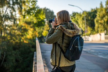 A young girl is walking around and takes pictures with a SLR camera