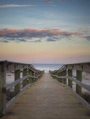 Obraz premium Walkway to the beach at dusk time with vibrant sky shot from a low angle 