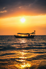 Fototapeta premium Bright red sunset on the beach with fishing boat in Cambodia, Sihanoukville.