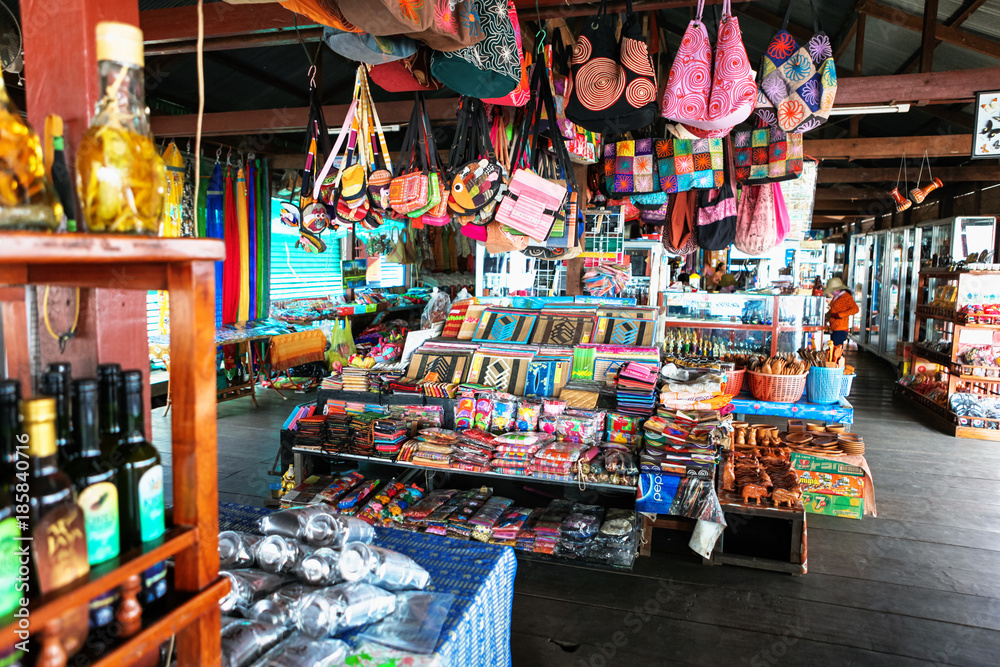 Wall mural beautiful and colourful silk and cotton Indian scarfs, bags and bottles sold in souvenir shop market stall