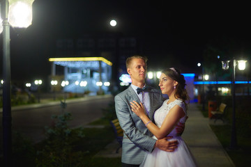 The bride and groom stand on the beautiful porch of the hotel at night