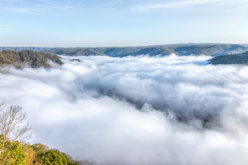 Mountains and fog, mist clouds in morning floating above forest trees, covering, blanketing valley in Grandview Overlook, West Virginia