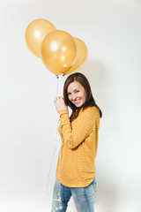 Beautiful European fun young happy woman in yellow clothes with shy charming smile, golden balloons, celebrating birthday, on white background isolated for advertisement. Holiday, party concept.