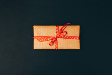 Top view of a box with a gift and a red ribbon
