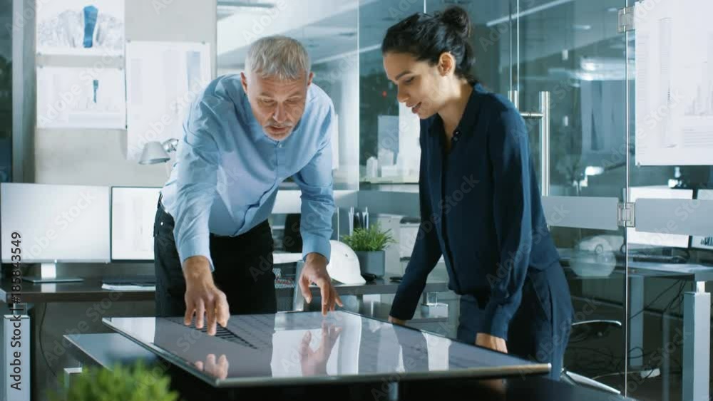 Poster senior male and young female architectural designers draw building concept on a graphics tablet disp