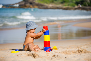 Kid plays with toys at the seashore in summertime