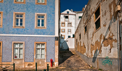 Fototapeta na wymiar Contrasting shot of an empty street in Alfama, the oldest district of Lisbon, Portugal, on the slope of Sao Jorge. Alfama boasts many historical attractions along with Fado bars and restaurants.