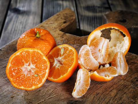 Fresh clementines freshly picked in slices and in wedges on wooden background