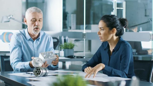 Experienced Male and Female Industrial Engineers have Discussion, They Work on a Machinery Component Design. They Office is Stylish and Modern Looking. Shot on RED EPIC-W 8K Helium Cinema Camera.