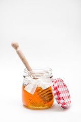 Close up of a decorative honey jar and honey spoon on a white background