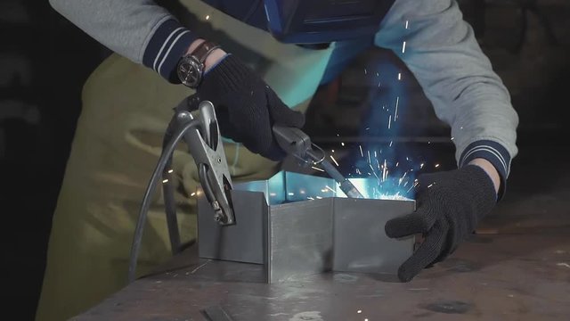 Blacksmith welding steel and iron in slow motion at his workshop, close-up.
