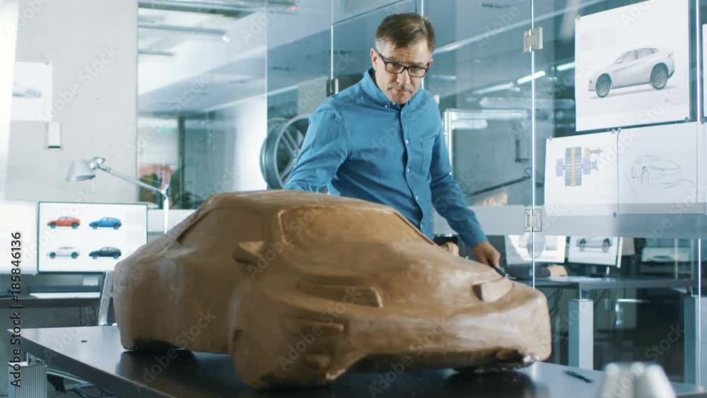 Poster experience automotive designer with a rake sculpts prototype car model from plasticine clay. shot on
