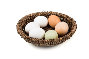 Farm fresh and commercial eggs in a bowl on a white background