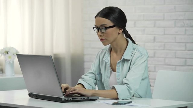 Young asian woman typing on laptop, writing flirty message on dating website