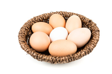 Farm fresh and commercial eggs in a basket on a white background