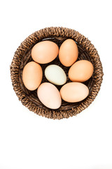 Farm fresh and commercial eggs in a basket on a white background