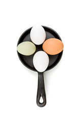 Farm fresh and commercial eggs on a frying pan on a white background