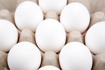 Commercial eggs in a carton on a white background