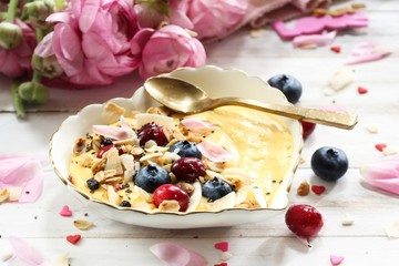 Valentine breakfast bowl mango smoothie granola and berries in heart shaped plate, selective focus