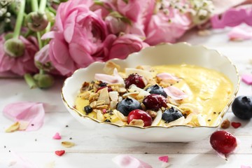 Valentine breakfast bowl mango smoothie granola and berries in heart shaped plate, selective focus