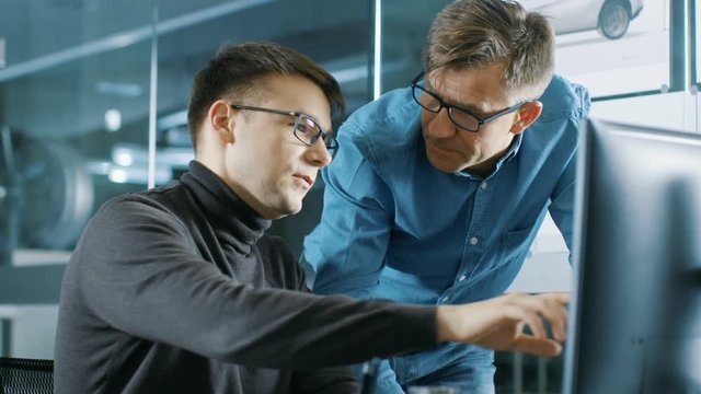 Experienced Senior Engineer Consults Young Designer about Project, They Have Discussion and Work on a Personal Computer. Shot on RED EPIC-W 8K Helium Cinema Camera.