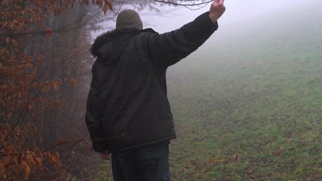 Man lifted branch and goes into fog - (4K)