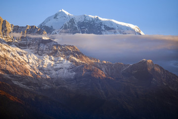 Edge of the Annapurna mountain range rises above the clouds and behind the slope of Fishtail mountain.