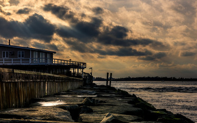 Sunbeams passing through the clouds over the pier on moody day. 