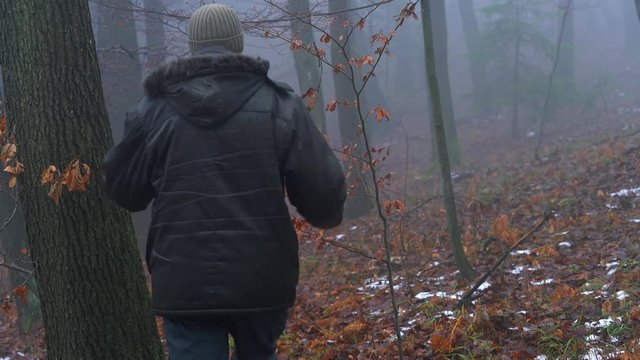 Man walking in snowy forest and goes into fog - (4K)