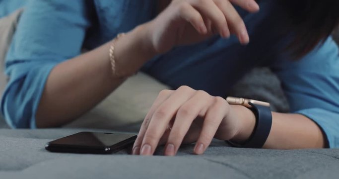Close up young woman hands uses a smart watches and phone mobile adult modern, screen appliance connection finger internet home slow motion