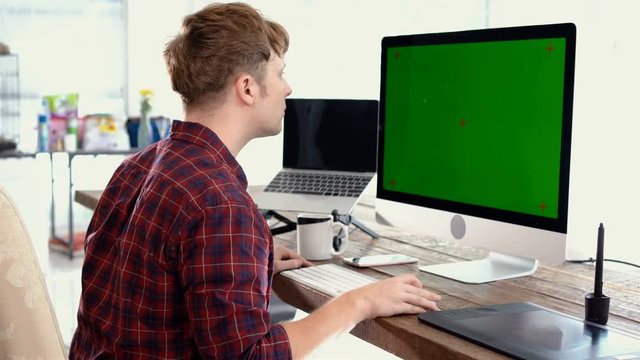 A young freelancer man using mouse and typing on keyboard