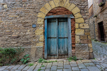 Fototapeta na wymiar Pale blue and worn door on the stone walls of a small town in Fr