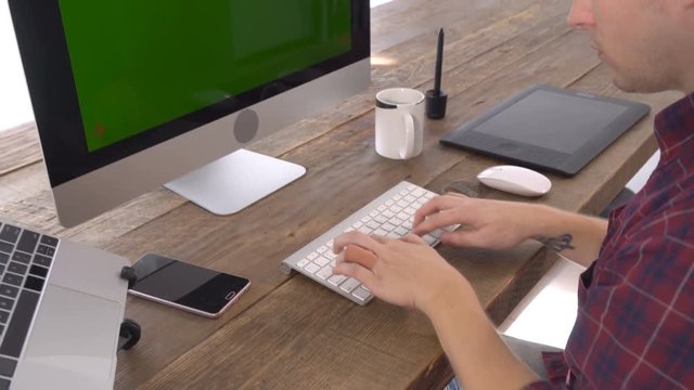 The freelancer male typing with green screen display