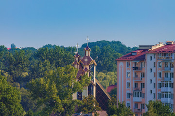 Modern buildings and church among the park trees, blue sky