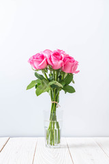 Fototapeta premium pink rose in vase on wood background