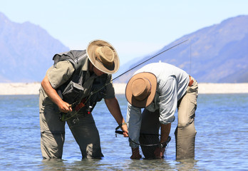 Fly Fisherman and Guide Catching and Releasing Trout on New Zealand River in Otago South Island