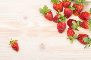 lot of scattered strawberries, on a light wooden background