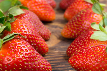 two rows of ripe red strawberries, on a wooden board