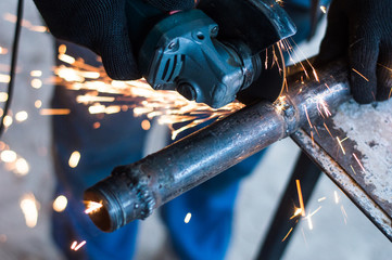 A man is working a metal pipe with a tool for cutting metal