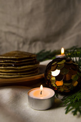 Pancakes with oranges on a Christmas table with candles