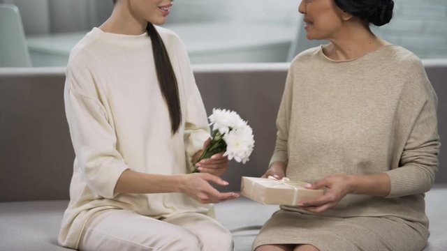 Brunette woman giving present to adult lady, anniversary celebration, birthday