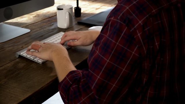 Close up hand male typing on wireless keyboard on wooden table