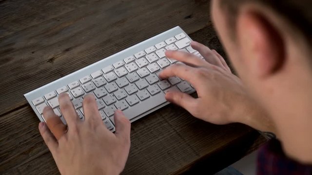 Close up the caucasian male is typing on wireless keyboard on wooden table
