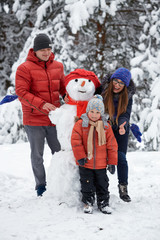 Fototapeta na wymiar winter fun. a girl, a man and a boy making a snowman.