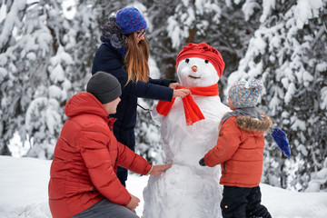 winter fun. a girl, a man and a boy making a snowman.