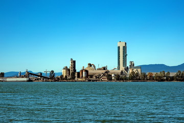 Cement Factory at the waterfrant of Fraser River at the bacground of blue sky and mountain range