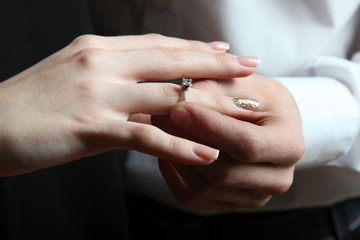 The guy puts the ring on the girl's finger. Close-up. 
